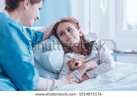 Smiling caregiver visiting happy, sick child in the health center Royalty-Free Stock Photo #1014875176