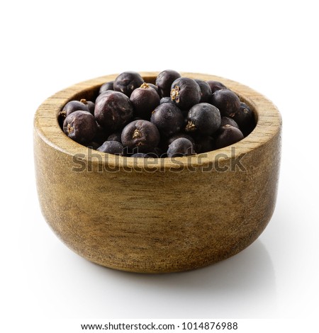 Dry juniper berries in dark wood bowl isolated on white. Royalty-Free Stock Photo #1014876988
