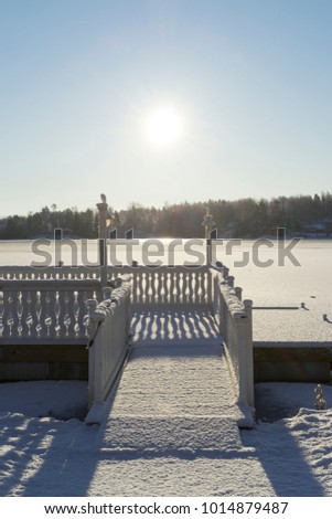 Beautiful nature and landscape photo of cold sunny winter day in Sweden Scandinavia. Nice clear blue sky at morning. Snow, wooden bridge and ice lake. Calm, peaceful and happy outdoors image.
