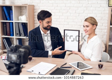 Businessman in suit and businesswoman in blouse showing diploma for business podcast. Blank diploma.