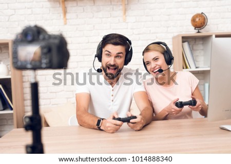 Man and woman podcasters in white shirts play video games for podcast. Royalty-Free Stock Photo #1014888340
