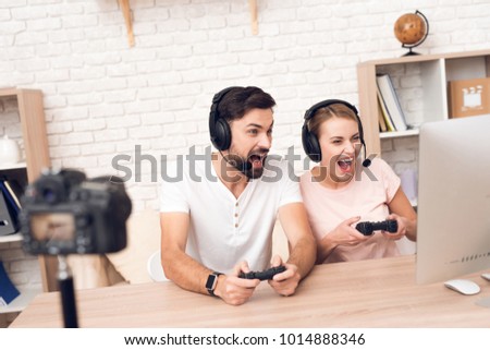 Man and woman podcasters in white shirts play video games for podcast. Royalty-Free Stock Photo #1014888346