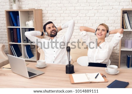 Man and woman podcasters in white shirts relaxing to music for radio podcast.