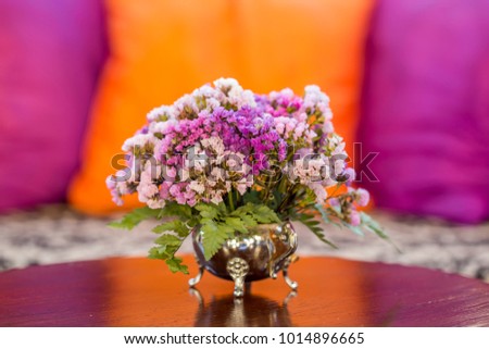 The violet or pink flowers in vast on the grass table with pillows in the living room , vintage style.