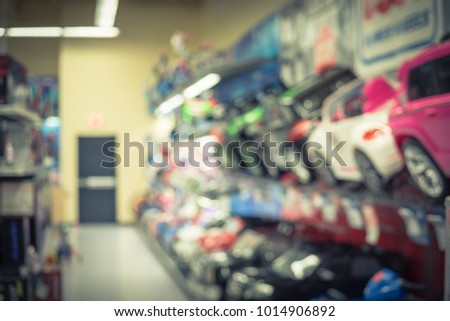 Blurred row of ride-on toy cars at toy retailer store in America. Vintage tone
