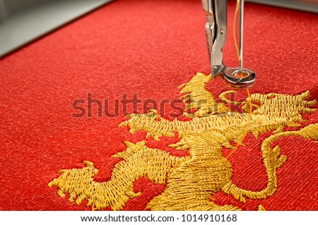 Close up picture embroidery design gold lion on red fabric embroider by machine, copy space on the left side.