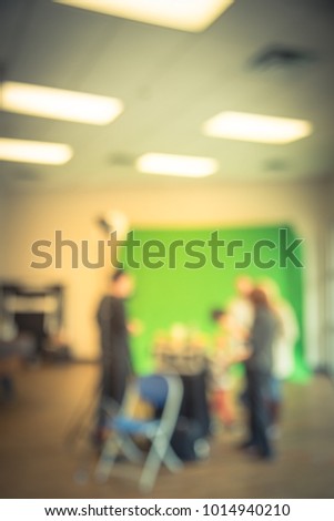 Blurred onsite photo booth at local event in Irving, Texas, USA. Professional photographer with assistants taking free family photos with large green screen backdrop, equipments. Vintage tone