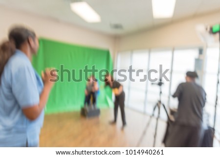 Blurred open space onsite photo booth at local event in Irving, Texas, USA. Photographer with assistant taking free family photos with large green screen backdrop, equipments.