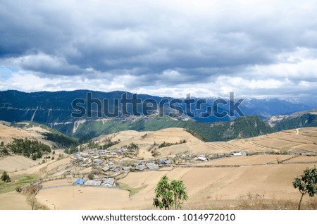 Outback countryside in China,foreground have yellow field and background had mountain,small hut