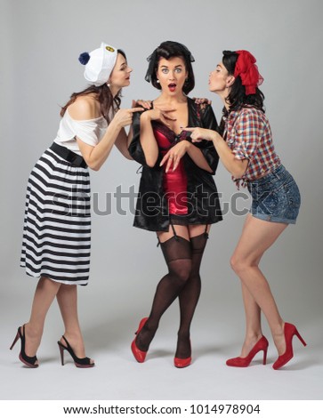 Three young women whispering gossip . Expressive emotions. Different role-playing costumes.