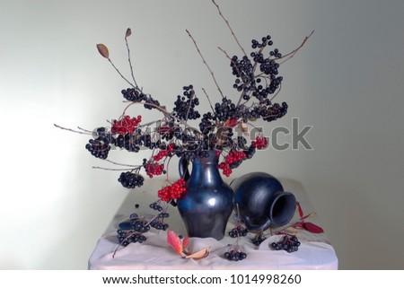 Autumn still life berries fireplaces, yellow leaves in a vase on a brown background.