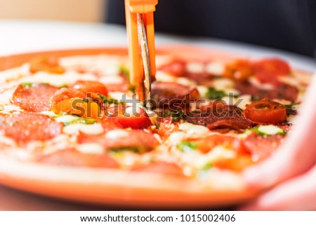 Close up circular knife cuts pizza