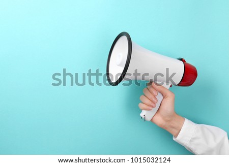 Woman holding megaphone on color background Royalty-Free Stock Photo #1015032124