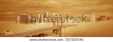 This is a sepiatone of the Brooklyn Bridge over the East River with the Manhattan skyline behind it. There is a morning fog enveloping the bridge.