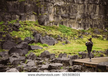 Female tourist hiker visiting a Pingvelir national park in Iceland. Tourist woman making a photo with her phone.Nature and environment appreciation 