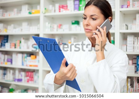 Beautiful young female pharmacist talking on the phone
