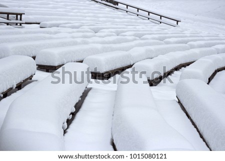 Open summer scene in winter. Snow on benches after a snowfall. Snowdrifts instead of spectators. Snow caps in the park. Moscow