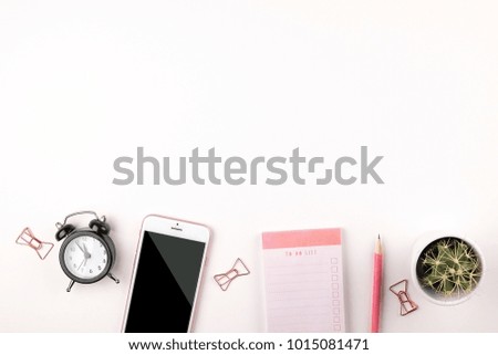Minimal feminine workspace, blank notebook, cactus, paper clip, pencil. Back to school concept. Girl's desk w/ pink supplies, mobile cell phone, alarm clock. Isolated, flat lay, copy space, background