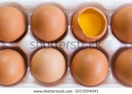 Close-up top view of raw chicken eggs and egg yolk on a cartoon box
