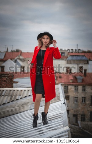 Girl in red and with black hat posing on the roof of old city.