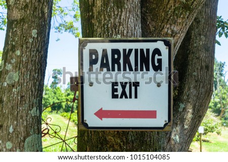 Outdoor parking exit sign directions on farm tree.