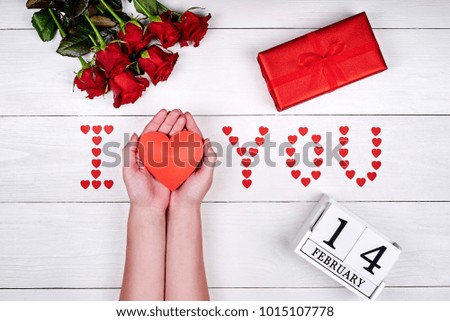 Valentines Day background with bouquet of roses, gift box. Sign I Love You made from red paper hearts and heart in woman hands, copy space. Love concept. Top view, flat lay