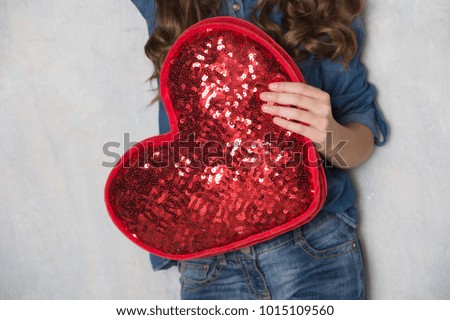 Valentine's Day. Beautiful girl in denim clothes with red heart.
