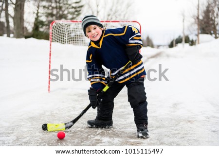 child playing hockey in street in winter season