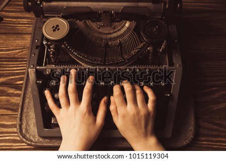 hands on a typewriter on a wooden background.