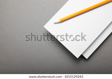 White paper flyer with pencil on a gray background.