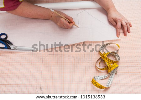tailor tracing the hand drawn clothing pattern on tracing-paper Royalty-Free Stock Photo #1015136533