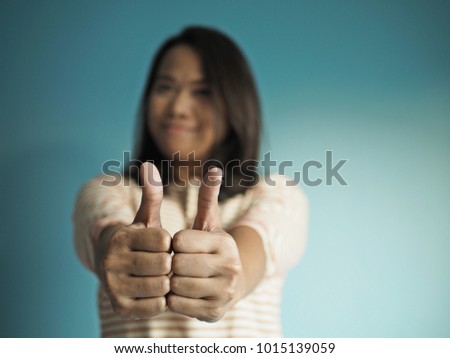 Positive woman giving two thumbs up on blue background. Life and business success concept! (selective focus on hands gestures, space for text)