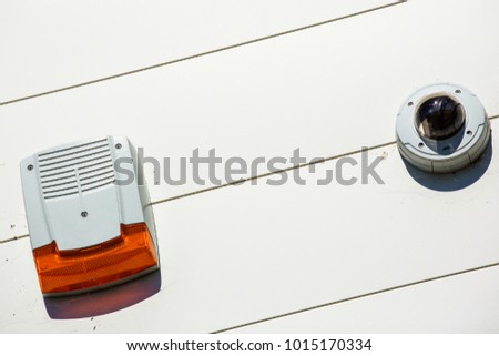 close up on a white security alarm box and cctv on a wall