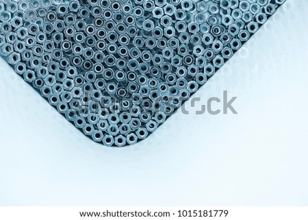 Lots of galvanized industrial steel nuts on a white background