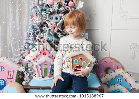 Happy little girl smile and playing by a Christmas tree. Christmas decoration, gingerbread houses