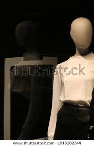 Close up view of an elegant female mannequin placed at a boutique window. Just 2 colors, white and black, at the storefront.  Fashion and beauty symbol. Nice design and simple composition.   