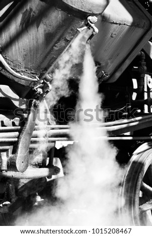 Hot steam is released from an historic steam train engine.