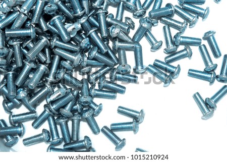 Lots of big industrial galvanized screws on a pile on white background