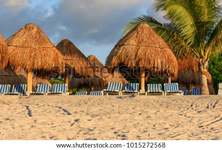  Stormy weather. Tropical sandy beach with palms, straw umbrellas and stripy lounge chairs.