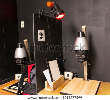 A dark room is set up with old fashion black and white enlargers ready to print pictures.