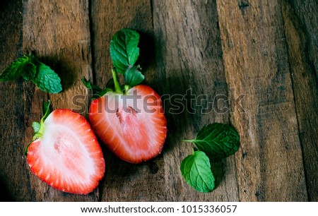 Strawberry red, half cut, lay on the old wood background.