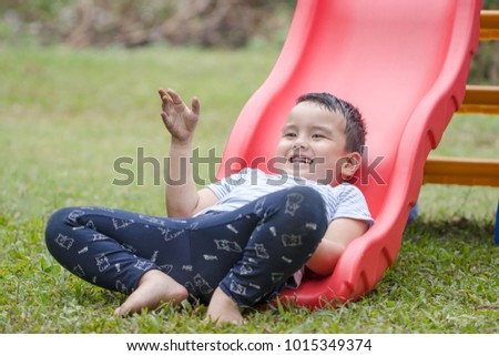 Portrait Thai boy play the slider in the playground in front of the house. He is cute and has a bright smile. Exercise in the morning for a healthy body. Soft focus and blur. Sport and game concept.