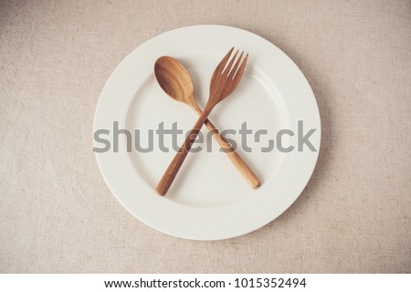 white plate with spoon and fork, Intermittent fasting concept, ketogenic diet, weight loss,  food crisis, restaurant and cafe close due to covid-19 coronavirus pandemic Royalty-Free Stock Photo #1015352494