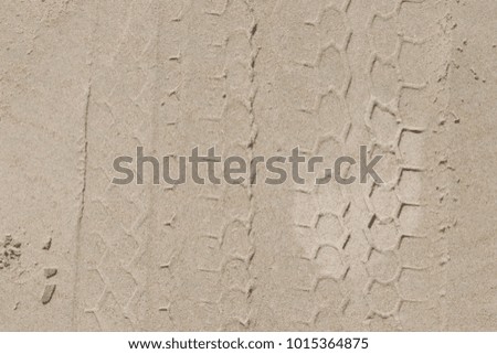 Car tyre prints on white beach sand