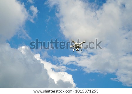 Flying drone in blue sky and clouds