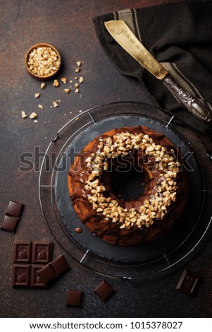 Chocolate and pumpkin bundt cake with chocolate glaze and walnut on dark concrete background. Selective focus. Top view. Copy space.