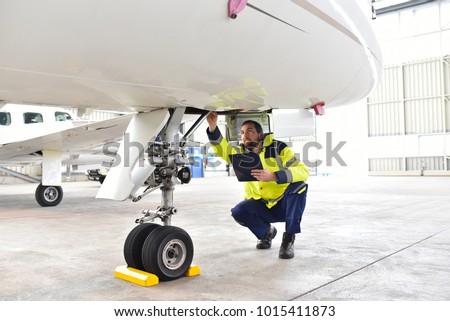 Ground personnel at the airport check the hydraulic system of the landing gear of the aircraft  Royalty-Free Stock Photo #1015411873