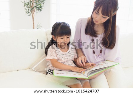 Japanese girls get to read a book on the couch to mom