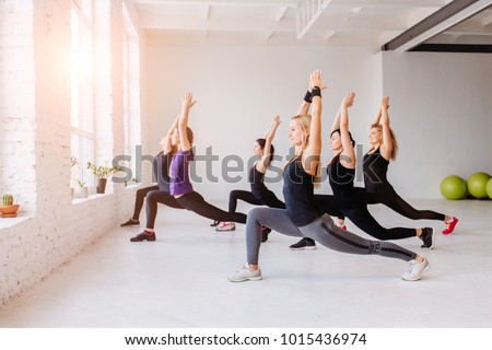 Group of women doing yoga, pilates and fitness and exercise indoors in white loft interior studio. Royalty-Free Stock Photo #1015436974