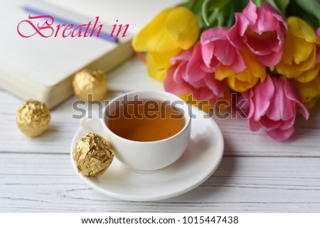 A motivation card "Breath in" - a photo with tulips, a cup of tea and a note book decorated with an elegant lettering